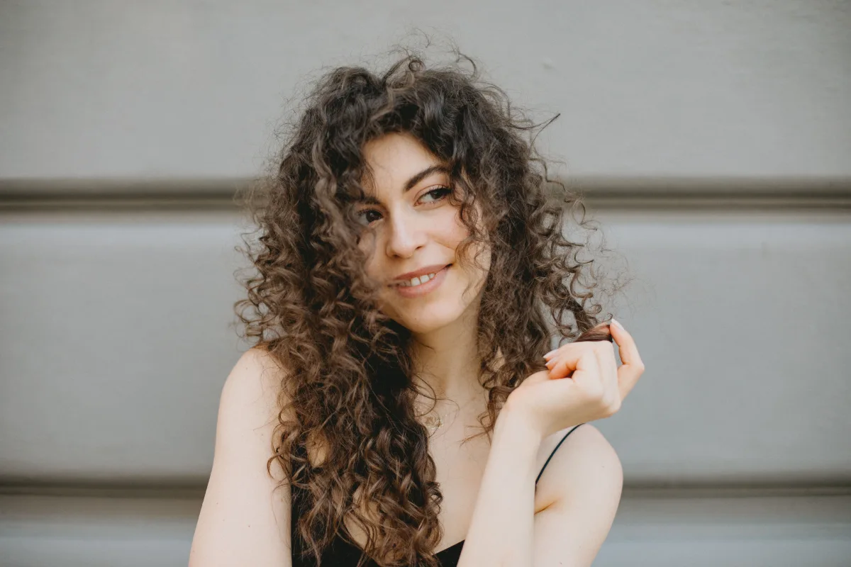 Femme aux cheveux bouclés, souriante, montrant ses magnifiques boucles naturelles