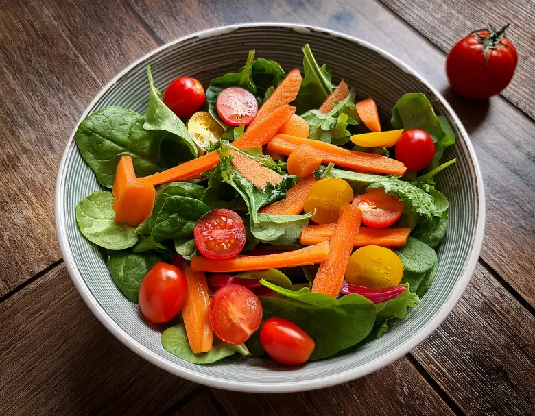 Salade colorée avec carottes, poivrons rouges, épinards et tomates, source de vitamines A et C