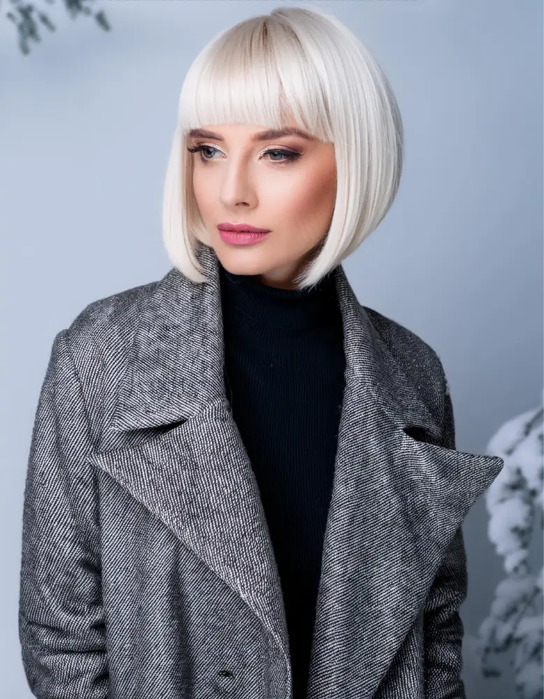 Femme avec un bob court classique sur cheveux blond cendré, portant un manteau d'hiver