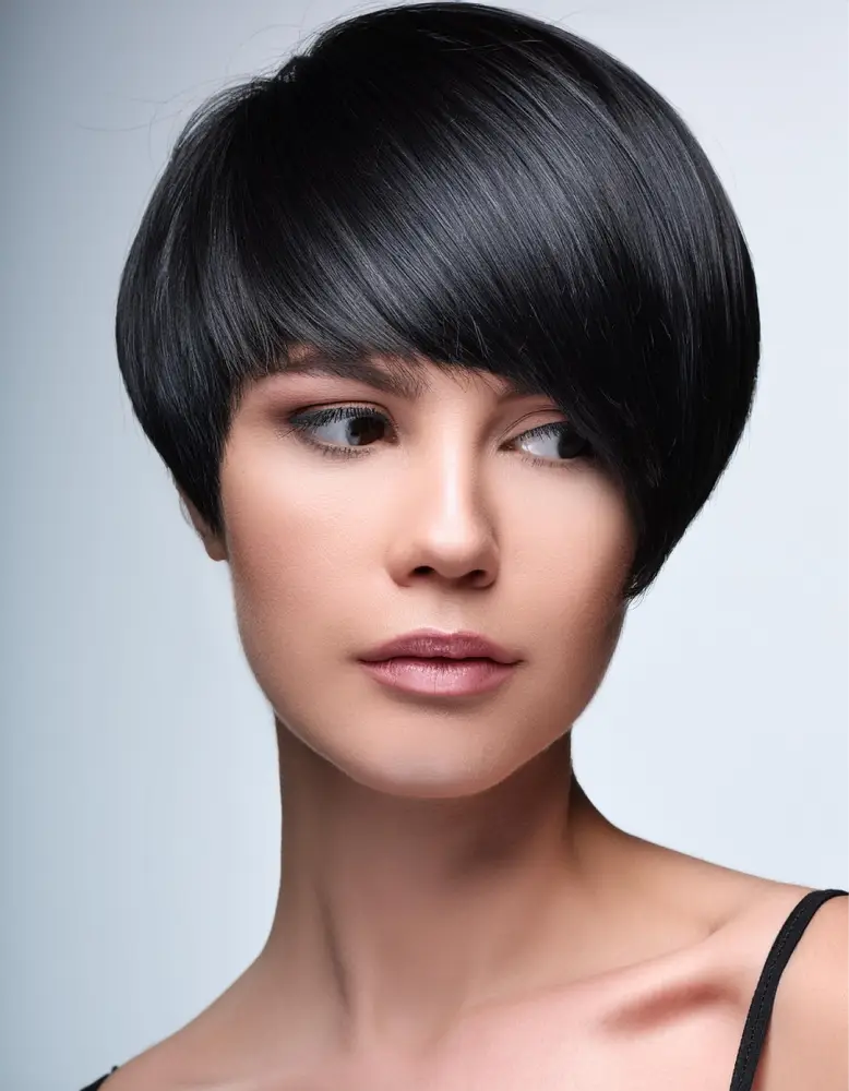 Femme avec une coupe pixie sleek sur cheveux noirs jais, fond minimaliste