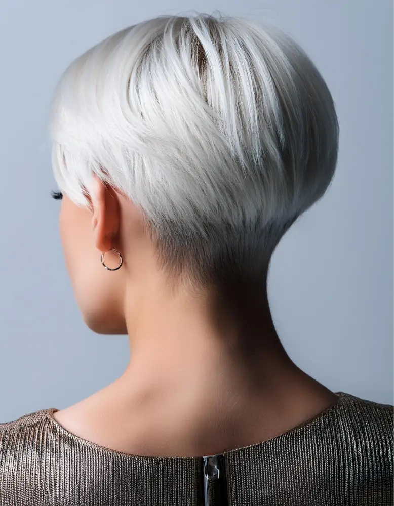 Femme avec une coupe pixie moderne sur cheveux blonds platine, fond minimaliste