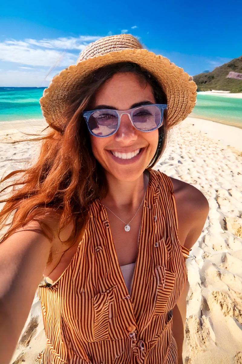 Créatrice Instagram souriante partageant ses moments de voyage sur une plage via un canal de diffusion Instagram