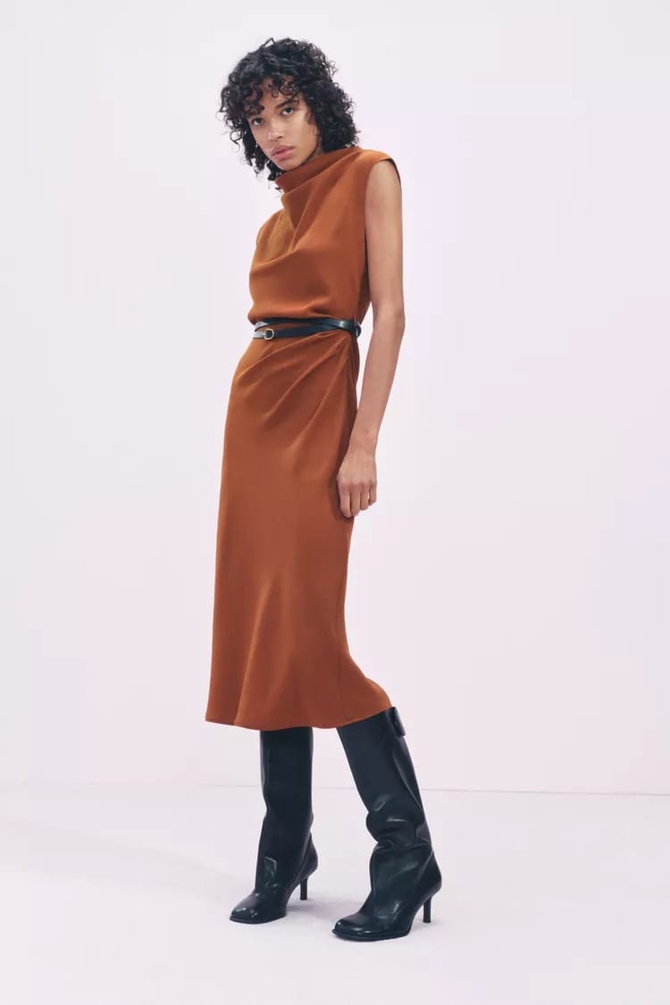 Femme portant une robe midi orange foncé Zara avec ceinture noire et bottes hautes, automne 2024