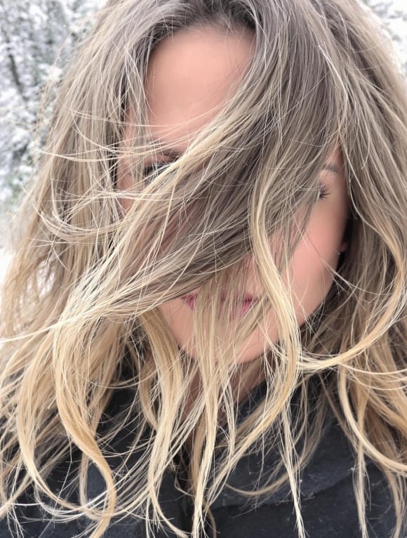 Femme avec des cheveux secs et abîmés en hiver, illustrant les effets du froid sur la chevelure