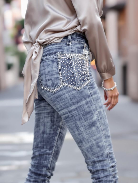 Femme portant un jean à strass avec une blouse en soie et des talons, parfait pour un look glamour et chic