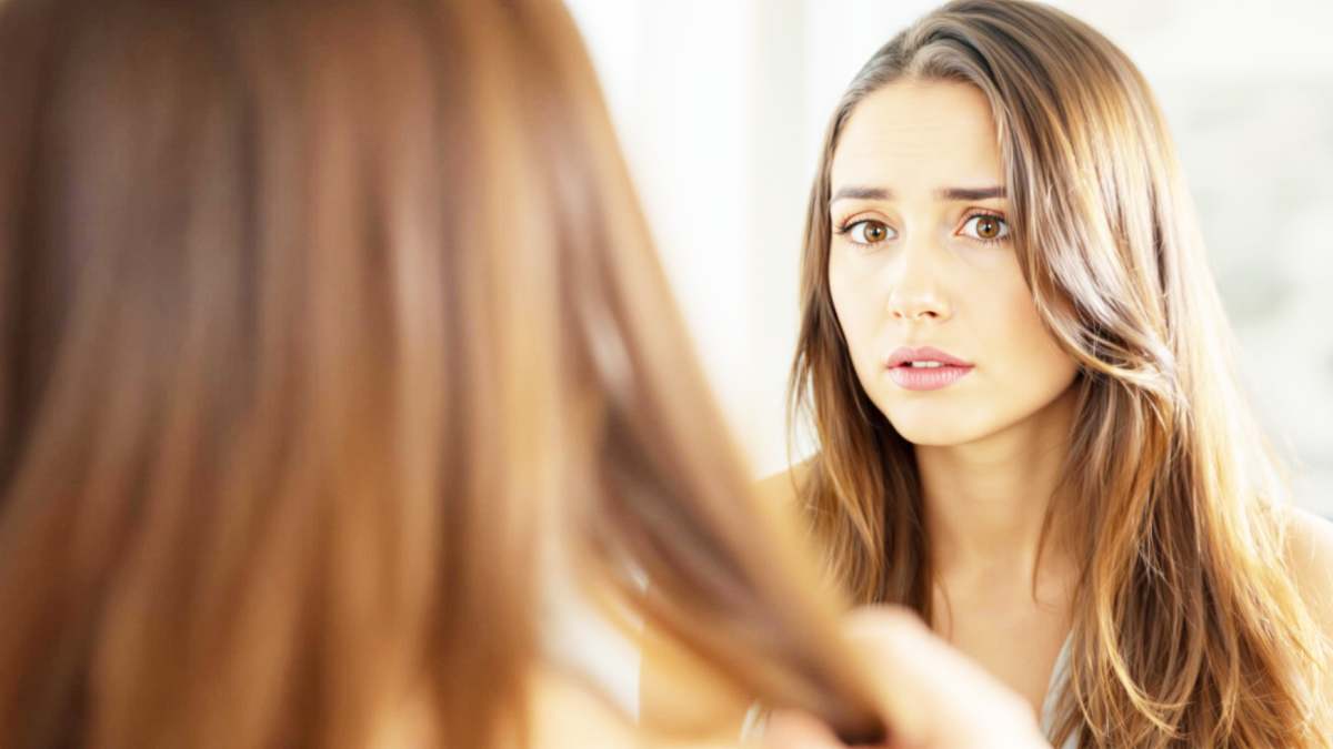 Femme inquiète devant le miroir, examinant ses cheveux