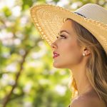 Femme avec un chapeau de paille vintage large brim se protégeant du soleil doucement