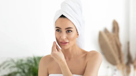 Femme dans salle de bain qui se démaquille les yeux avec un coton démaquillant