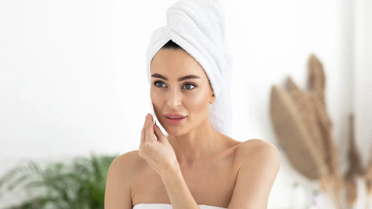 Femme dans salle de bain qui se démaquille les yeux avec un coton démaquillant