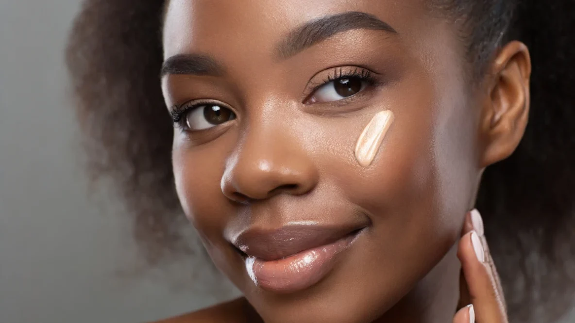 Jeune fille à la peau grasse qui applique du fond de tient