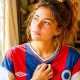 Jeune femme touchant le tissu de son maillot de football vintage, regard nostalgique en gros plan