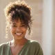 Femme afro souriante aux cheveux bouclés et crépus naturels, symbole de la beauté des cheveux texturés et de leur soin adapté