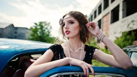 Photo d'une fille en tenue Gatsby accoudée sur une voiture des années 20