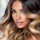 Femme aux cheveux noirs avec un balayage miel, mettant en valeur des reflets chauds et lumineux