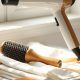 Sèche-cheveux et brosse ronde posés sur un plan de marbre clair, nature morte illustrant les outils du brushing