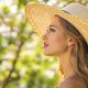 Femme avec un chapeau de paille vintage large brim se protégeant du soleil doucement