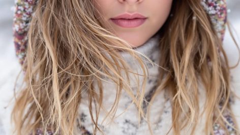 Femme avec des cheveux secs et abîmés en hiver, illustrant les effets du froid sur la chevelure