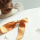 Chignon simple vu de dos à la nuque, épingles et ruban noué posés sur un marbre blanc, lumière naturelle