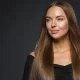 Combien de temps dur un soin à la Kératise après lissage de cheveux - Model femme au cheveux longs et brillant sur fond neutre