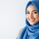 Une femme élégante portant un hijab en soie rose pastel, adapté à sa morphologie et à son teint, souriante et posant dans une lumière naturelle avec un fond blanc lumineux. Le choix parfait pour allier style et confort.
