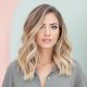 Femme avec un visage rond et des cheveux mi-longs ondulés, coiffée avec une raie sur le côté pour un look chic