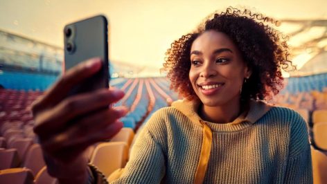 Créatrice souriante utilisant un canal de diffusion Instagram pour se connecter avec son audience dans un cadre extérieur