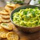 Bol de guacamole à la courgette avec coriandre et citron, servi avec des crackers