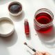 Nature morte de produits de maquillage Halloween : fard blanc, fard noir, faux sang et accessoires sur marbre clair