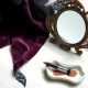 Nature morte beauté aux tons prune et noir sur marbre blanc, évoquant le maquillage soft goth de Mercredi Addams