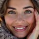 Femme avec une peau lumineuse et douce, entourée de neige et portant une écharpe, représentant une peau bien hydratée et protégée en hiver.