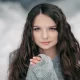 Jeune fille aux cheveux long et soyeux sous la neige cet hiver