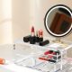 Organisateur de maquillage transparent à tiroirs et miroir, posé sur un plan en marbre blanc dans une lumière naturelle
