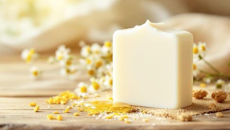 Savon au lait d’ânesse posé sur une surface en bois avec des fleurs de camomille