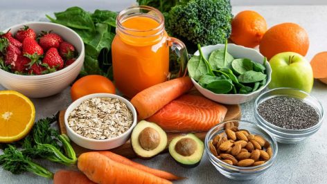 Assortiment de sources naturelles de vitamines : carottes, épinards, patates douces, agrumes, saumon, noix, graines et plats équilibrés pour une alimentation saine