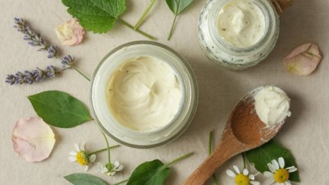 Cosmétiques naturels : pots de crème, feuillages et fleurs séchées sur fond neutre