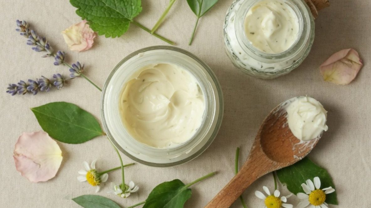 Cosmétiques naturels : pots de crème, feuillages et fleurs séchées sur fond neutre